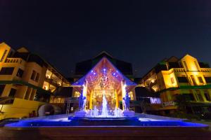 a fountain in front of a building with blue lights at Inn Come Hotel Chiang Rai in Chiang Rai