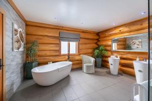 baño con bañera blanca y paredes de madera en The Log Cabins at The Vu en Bathgate