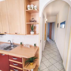 una cucina con armadi in legno, lavandino e corridoio di Salento Delizioso appartamento con ampia corte a Torre San Giovanni Ugento