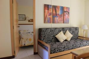 a living room with a bed, couch and a painting on the wall at Apartamentos Viña del Mar in Benidorm