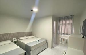 Una habitación blanca con dos camas y una ventana. en Veleiro Hotel MCZ, en Maceió