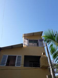 een geel gebouw met een palmboom ervoor bij cantinho bom in Ubatuba