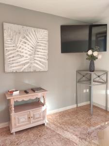 a living room with a table and a tv on the wall at Hotel Manzanito in Antequera