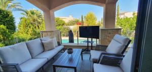 ein Wohnzimmer mit einem Sofa, Stühlen und einem TV in der Unterkunft Phaedrus Living Amorosa 13 Beachside Villa in Polis Chrysochous