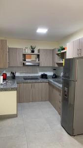 cocina con armarios de madera y nevera de acero inoxidable en Garzota Suites Gardens, en Guayaquil