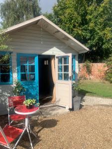 um pequeno barracão com uma porta e uma mesa em frente em The Cabin em Spixworth