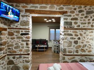 a room with a stone wall with a tv on the wall at Dream Nest Meteora in Kalabaka