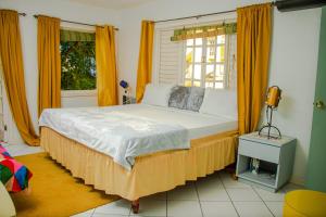 ein Schlafzimmer mit einem großen Bett mit orangefarbenen Vorhängen und einem Fenster in der Unterkunft E 20 Mystic Ridge ocho Rios in Ocho Rios + 37 Fotos