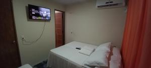 a small room with a bed with a tv on the wall at Vila dos Bangalôs in Barreirinhas
