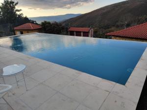 a large blue swimming pool with a table and a chair at Casa do Rancho - Turismo Rural in Paranhos