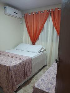 Schlafzimmer mit einem Bett und einem Fenster mit Vorhängen in der Unterkunft Vila dos Bangalôs in Barreirinhas