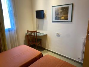 um quarto com uma cama, uma cadeira e uma televisão em Hostal Meson Pepa em Logroño