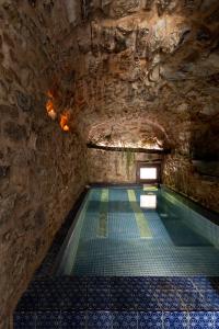 WUNDERGARTEN Private Home Spa في Gratteri: مسبح في كهف بجدار حجري