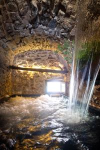 WUNDERGARTEN Private Home Spa في Gratteri: نفق حجري مع شلال في مبنى حجري