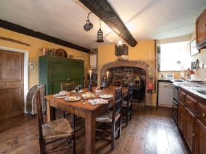 a kitchen with a wooden table with chairs and a fireplace at The Old Priory Cottage in Dunster