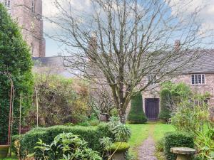 a garden with a tree in front of a building at The Old Priory Cottage in Dunster