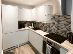 a kitchen with white cabinets and a stove at Pass the Keys Superb 1Bed Flat in Fabulous West End in Glasgow