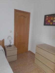 a bedroom with a bed and a dresser and a door at Apartamento Sagunto frente a Renfe in Sagunto