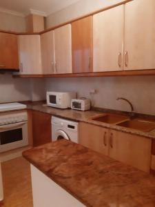 a kitchen with wooden cabinets and a sink at Apartamento Sagunto frente a Renfe in Sagunto