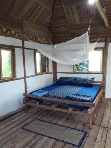 Cama en habitación con mosquitera en ZIONZURI ARTS ECOVILAGE TREE HOUSE, en Mbwamaji