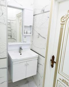 a white bathroom with a sink and a mirror at Премиум квартира возле метро in Baku