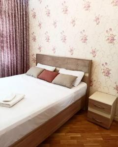 1 dormitorio con 1 cama con sábanas blancas y almohadas rojas en Премиум квартира возле метро, en Baku