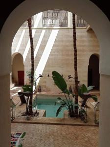 a swimming pool in a building with palm trees at Dar al Sultan in Marrakech