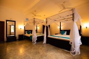 a bedroom with two beds with mosquito nets at International Beach Hotel & Restaurant in Hikkaduwa