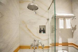 a shower with a glass door in a bathroom at Saptapuri by Royal Orchid Hotels Limited Varanasi in Varanasi +48 photos