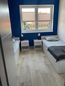 a small bedroom with a bed and two windows at Apartamenty na Zaciszu in Kąty Rybackie