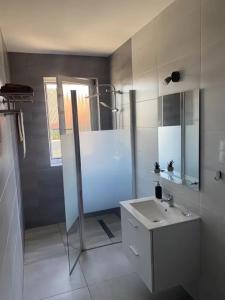 La salle de bains blanche est pourvue d'un lavabo et d'une douche. dans l'établissement Apartamenty na Zaciszu, à Kąty Rybackie