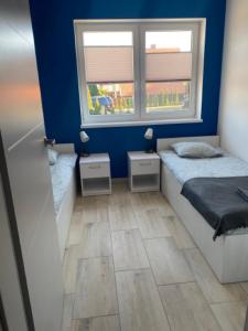 um pequeno quarto com uma cama e duas janelas em Apartamenty na Zaciszu em Kąty Rybackie