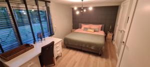 a bedroom with a bed and a desk and a window at Bij Ons Naast in Nuenen