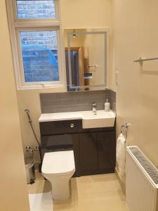 baño con lavabo y aseo y ventana en London Luxury Spacious 2 Bedroom Apartment 4 mins from Ilford Stn. FREE parking, en Londres