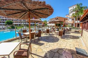 an outdoor patio with tables and chairs and an umbrella at Paradise Gardens - Golf del Sur in San Miguel de Abona