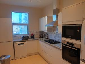 una cocina con armarios blancos y una ventana en London Luxury Spacious 2 Bedroom Apartment 4 mins from Ilford Stn. FREE parking, en Londres