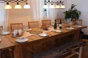 una larga mesa de madera con sillas y botellas de vino en Relaxhouse, 