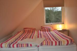 a bed with a striped blanket and a window at Relaxhouse in Håkantorp