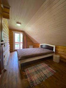 sypialnia z dużym łóżkiem w drewnianym pokoju w obiekcie Котедж На Лузі w mieście Verkhne-Studënyy