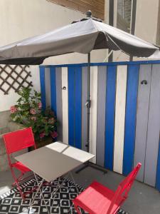 - une table, 2 chaises et un parasol sur la terrasse dans l'établissement Appartement Haute Ville meublé avec cour privative, à Granville