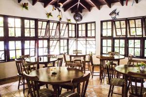 a restaurant with tables and chairs in a room with windows at Pousada Recanto dos Tangaras in Juquei