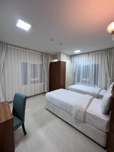 a hotel room with two beds and a chair at Grand Orchid Hotel Apartment in Duqm