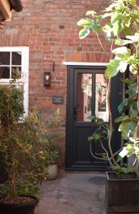 a black front door of a brick house with plants at The Gardener's Cottage in Leominster