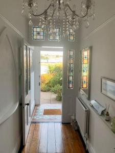 a room with a hallway with a chandelier and a door at A unique and spacious river front property in Shaldon