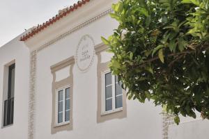 biały budynek z dwoma oknami i drzewem w obiekcie Casa do Brasão w mieście Marvão