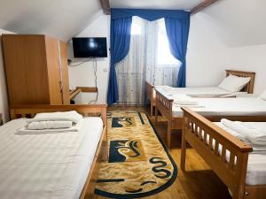 a dorm room with three beds and a television at Pensiunea Fortuna in Gorgova