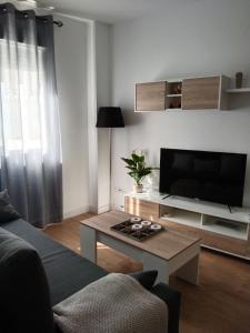 uma sala de estar com um sofá e uma televisão em APARTAMENTO EL LLANO em Lucena