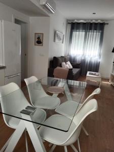 uma sala de estar com uma mesa de vidro e cadeiras brancas em APARTAMENTO EL LLANO em Lucena
