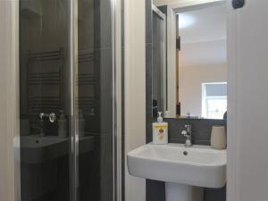 a bathroom with a sink and a shower with a mirror at Pen Parc in Bryn-crug