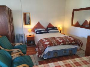 um quarto com uma cama e uma cadeira em Kaapsche Draai em Kaapsehoop